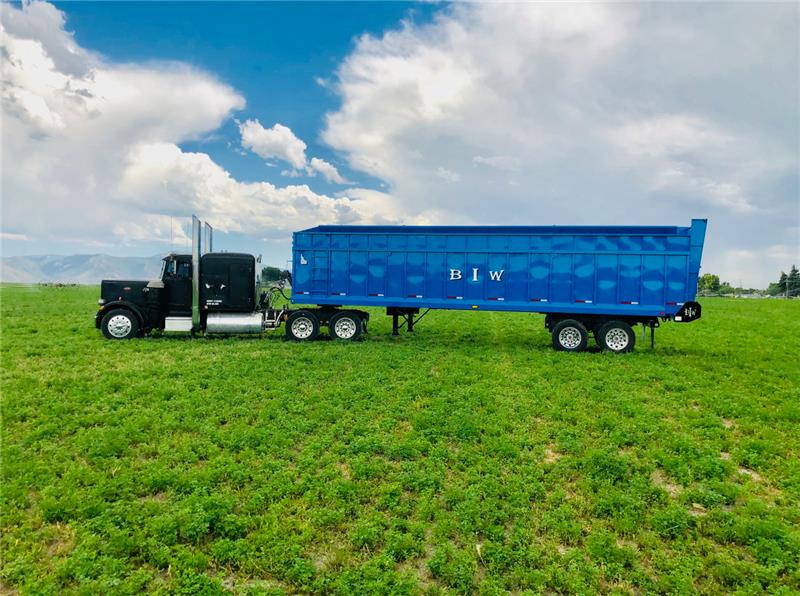 Blue BIW custom silage trailer hitched to a semi truck in an Idaho hay field